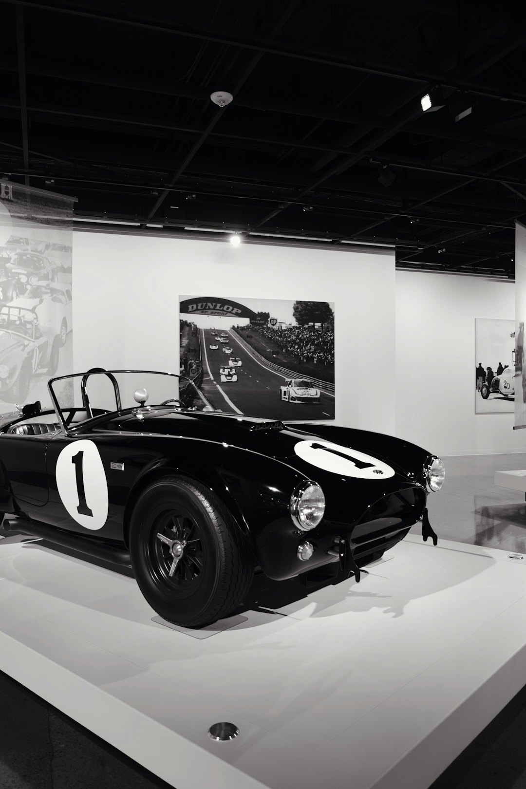Archive of black and white photographs of classic automobiles pinned to a wall