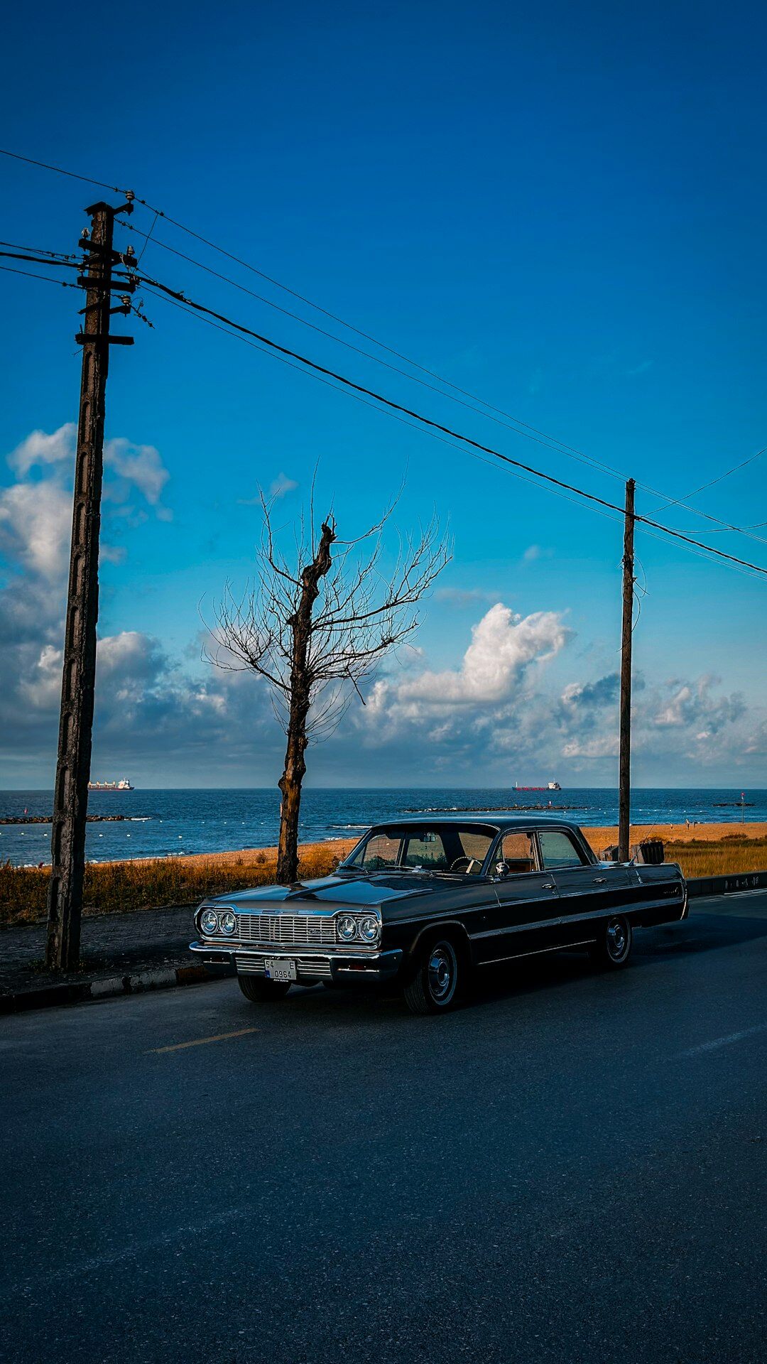 Classic sports car driving on a coastal road near Punta del Este at dusk